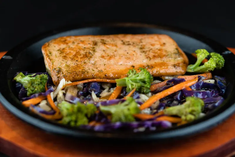 Salmão selado na chapa sobre legumes salteados
