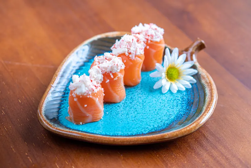 Dyo de Kani: peças de salmão cobertas de kani em prato azul de cerâmica