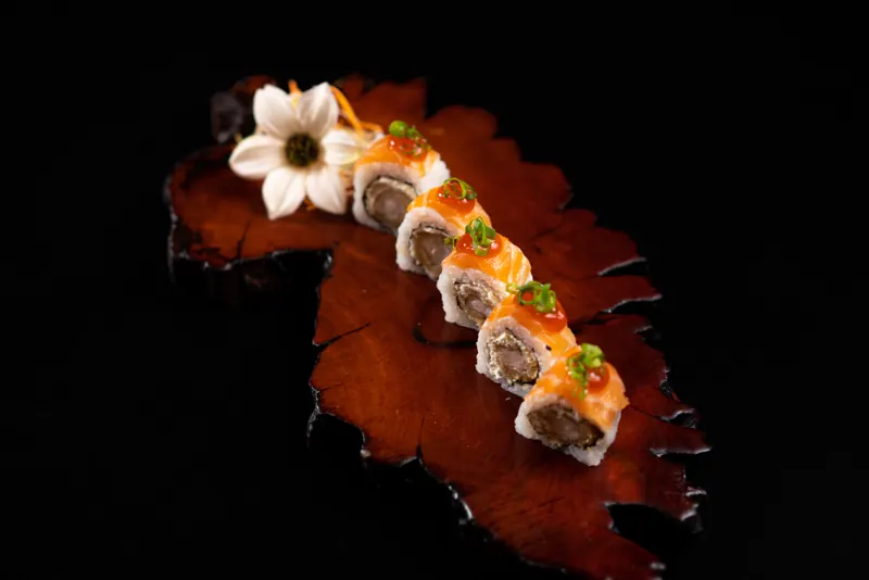 Uramaki de salmão com camarão em tábua de madeira rústica e flor branca